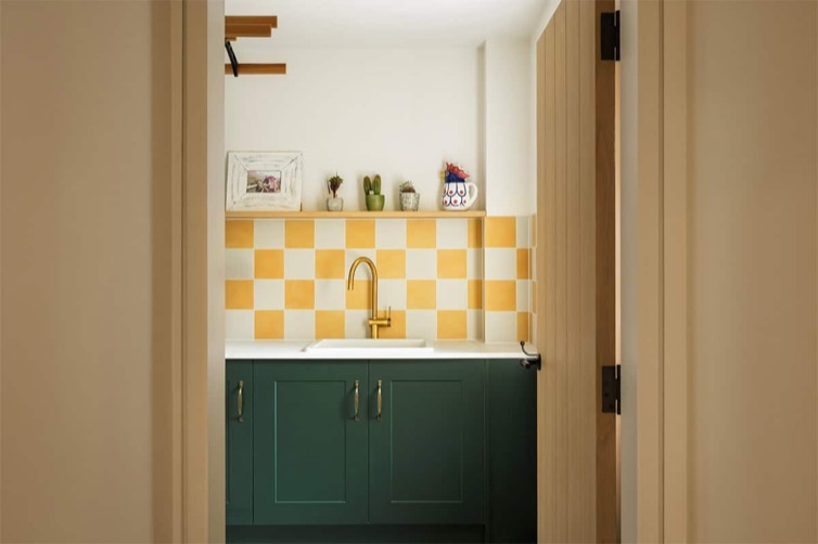 Hazelbridge Cottage utility room with green cabinets and yellow checkerboard tile splashback